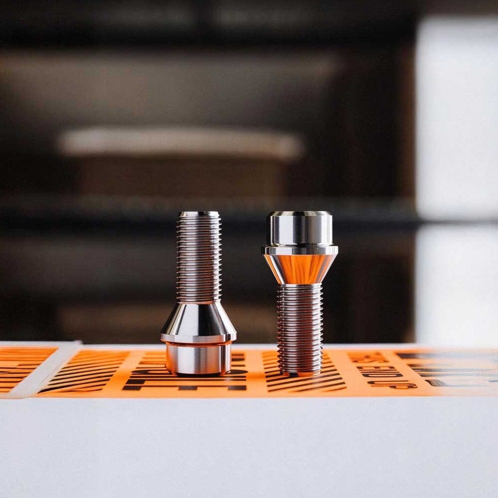 Precision CNC machined wheel lug bolts featuring 60-degree conical taper seat and threaded shank for aftermarket wheel fitment.